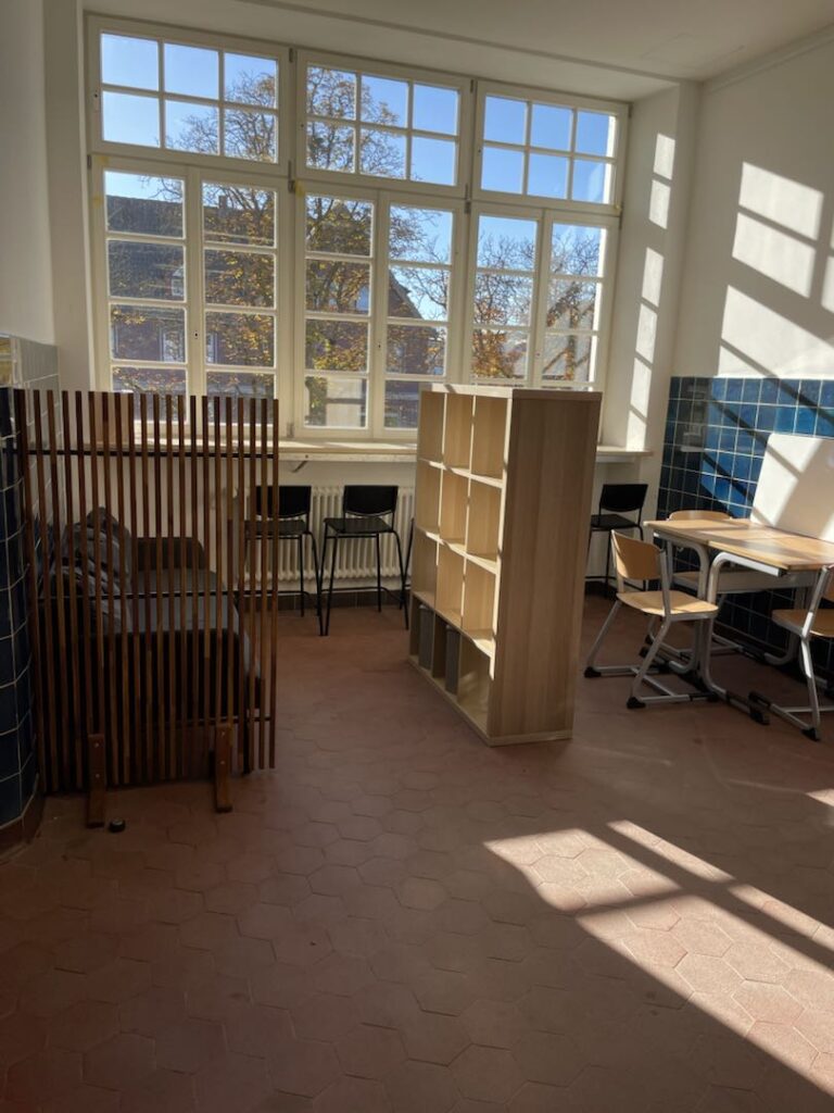 Fertig eingerichtete Ecke im Schulhaus mit Regal, Hockern, Tischen und Stühlen